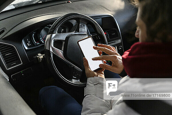 Man navigating through smart phone while sitting in car