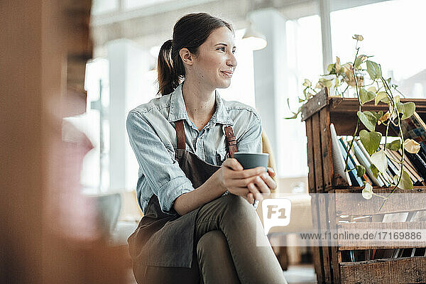 Lächelnde Managerin mit Kaffeetasse  die in einem Café wegschaut