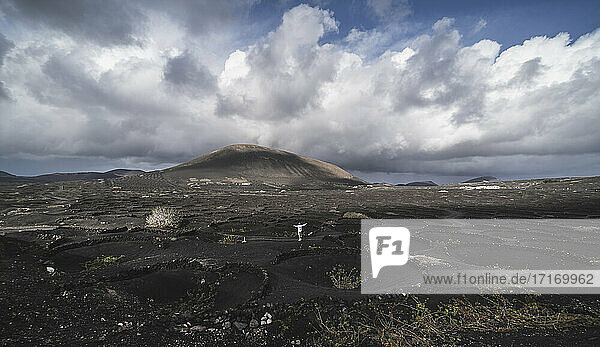 Male tourist with arms outstretched standing on black volcano ash at El Cuervo Volcano  Lanzarote  Spain
