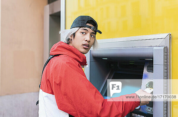 Young man withdrawing money at ATM machine