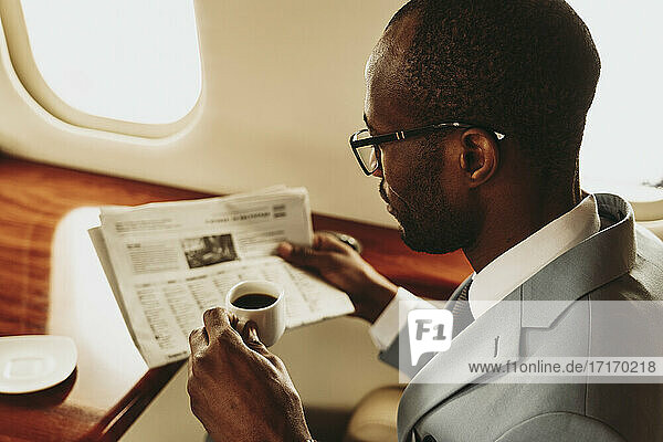 Businessman reading newspaper while traveling in airplane