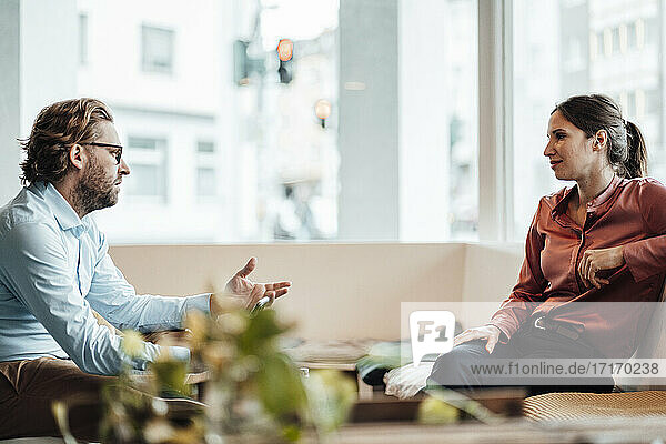 Geschäftsmann diskutiert während eines Treffens mit einer Kollegin in einem Cafe