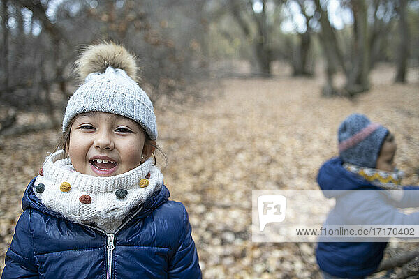 Cute girl with brother enjoying in forest during autumn