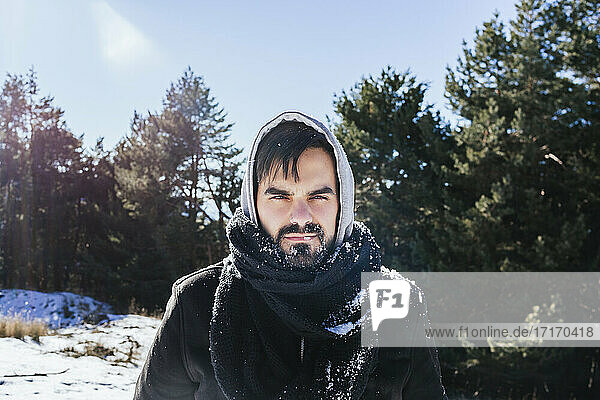 Bearded man in warm clothing standing on snow covered land against sky