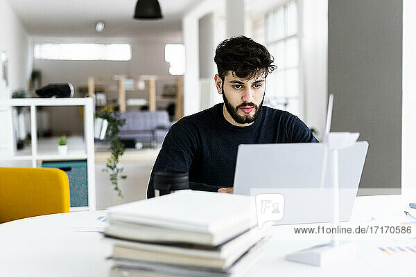 Young businessman using laptop in creative office