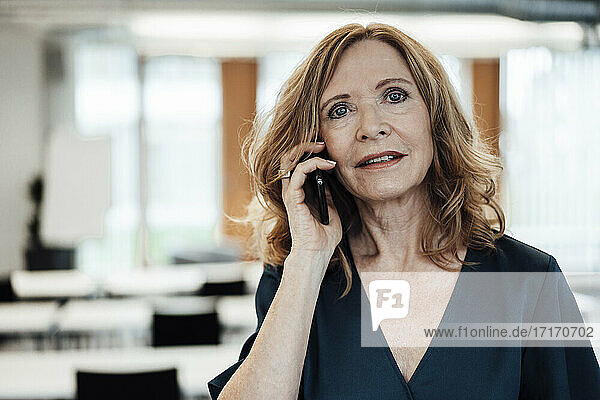 Geschäftsfrau  die im Büro mit einem Smartphone telefoniert