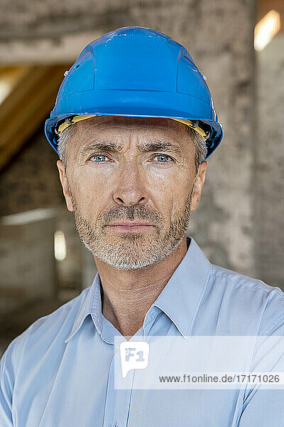 Architect wearing hardhat staring while standing at construction site