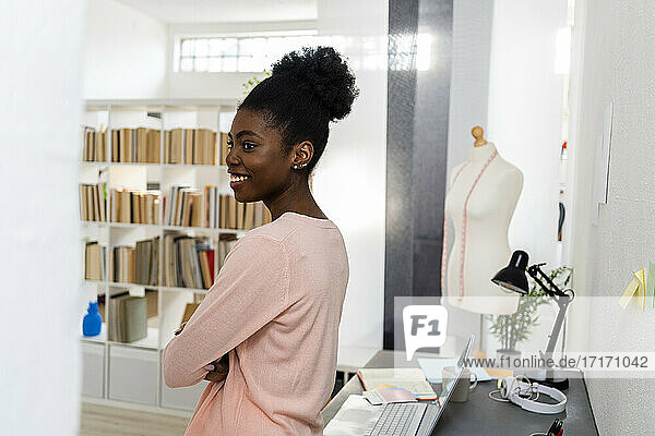 Modedesigner lächelnd im Büro zu Hause stehend