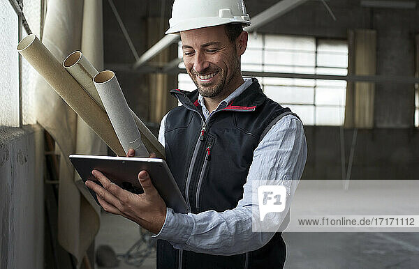 Smiling building contractor using digital tablet while standing at construction site