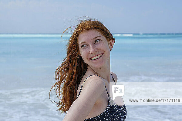 Lächelnde Frau  die wegschaut  während sie am Meer steht
