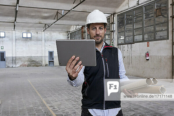 Male engineer using digital tablet while working in building at construction site