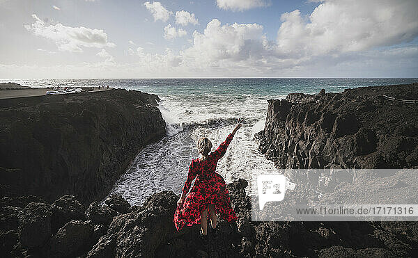 Junge Frau zeigt eine Friedensgeste  während sie auf einem Berg in Los Hervideros  Lanzarote  Spanien steht