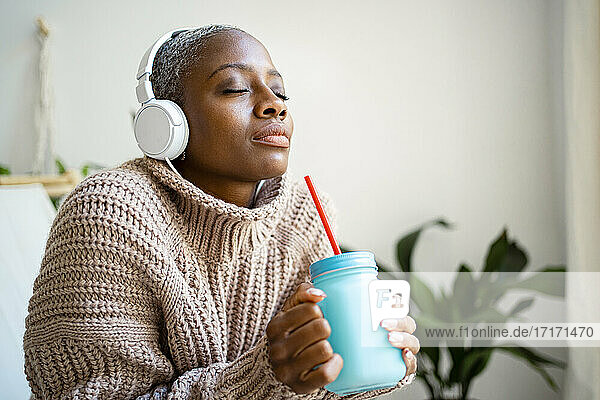 African woman with eyes closed listening music at home