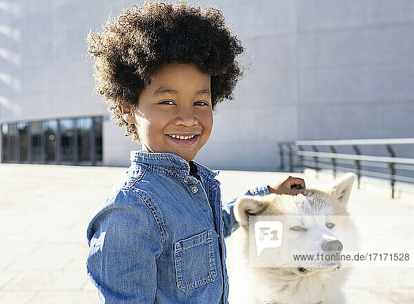 Lächelnder Junge spielt mit Hund im Freien