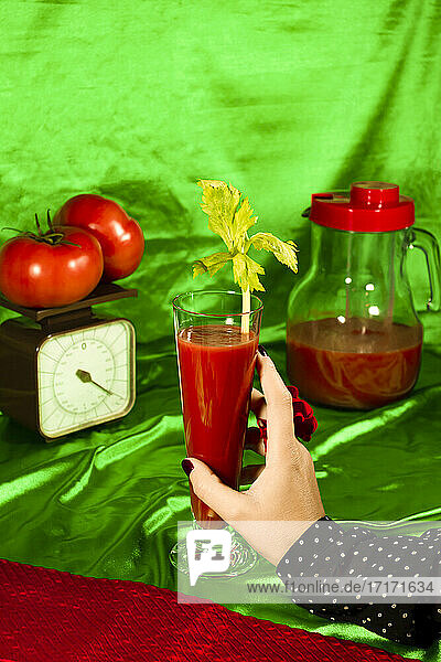 Frau hält Glas Tomatensaft mit Sellerieblatt