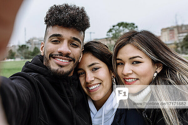 Young man with female friends taking selfie at park