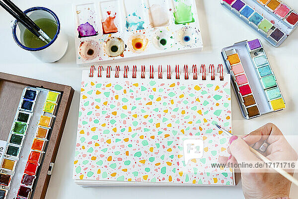 Painting pastel colors terrazzo pattern with watercolors on spiral notebook