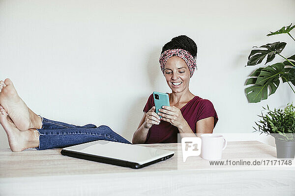 Eine Unternehmerin ruht sich aus  während sie ihr Smartphone im Büro zu Hause an der Wand benutzt