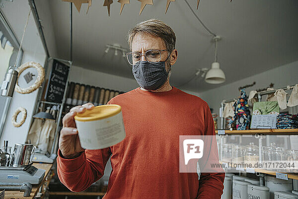 Älterer Mann prüft das Etikett eines Lebensmittelbehälters in einem Zero-Waste-Shop während einer Pandemie