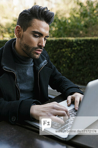 Handsome man using laptop while sitting at table
