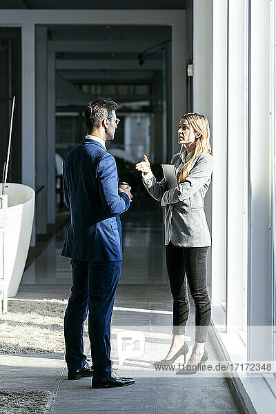 Businesswoman stretching hand toward partner while standing in office