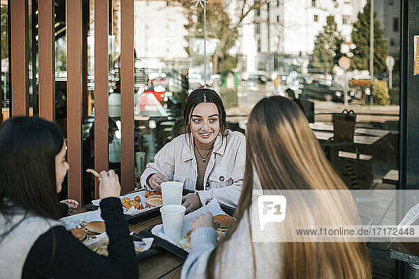 Weibliche Freunde unterhalten sich bei einem schnellen Essen in einem Restaurant im Freien
