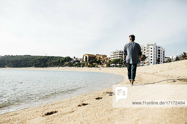 Mann spaziert am Strand an einem sonnigen Tag
