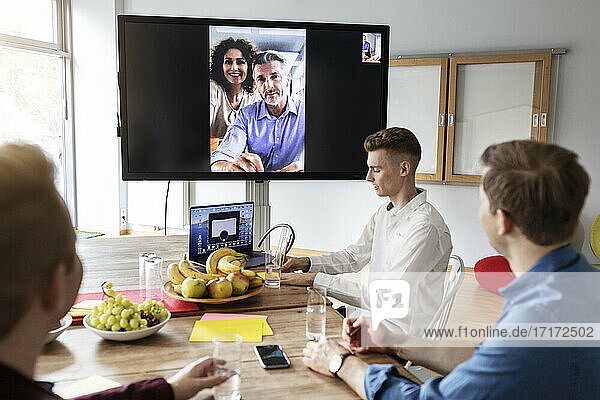 Entrepreneurs on video call having meeting with colleague sitting in office