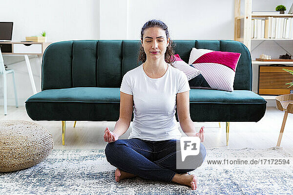 Young woman meditating while sitting at home