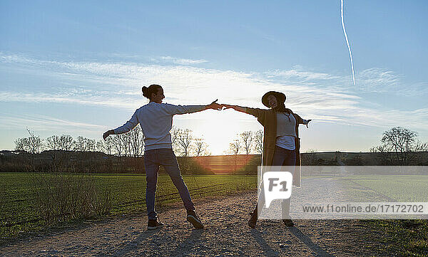 Couple dancing on land against sky during sunset