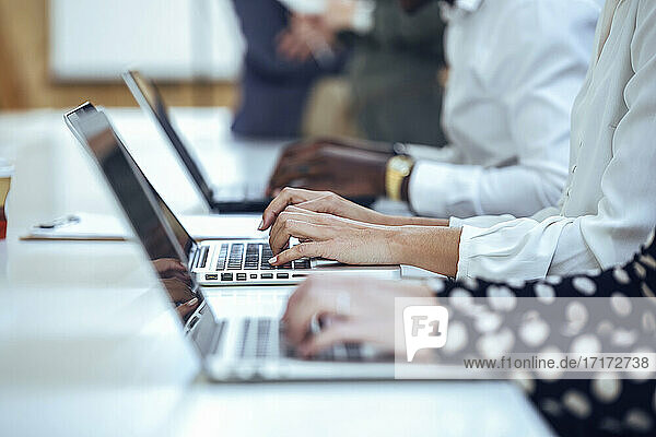 Geschäftskollegen beim Tippen mit dem Laptop am Schreibtisch im Coworking-Büro