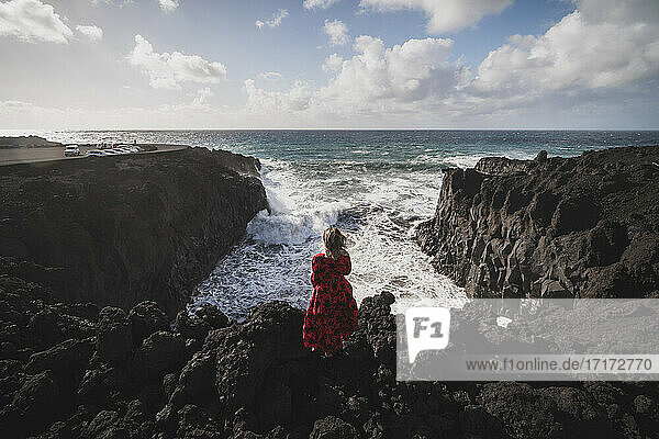 Frau mit Blick auf das Meer  während sie auf einem Berg in Los Hervideros  Lanzarote  Spanien steht