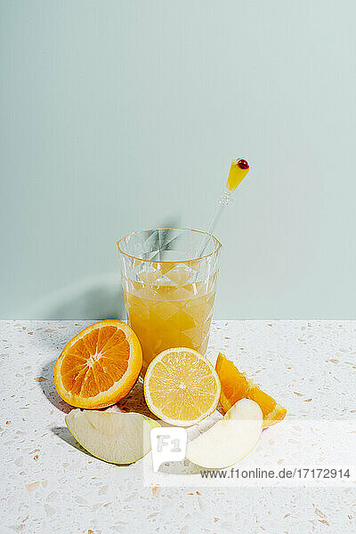 Summer fruit juice with orange  lemon and apple on terrazzo marble against wall