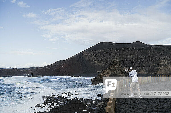 Männlicher Tourist beim Fotografieren vom Aussichtspunkt in El golfo  Lanzarote  Spanien