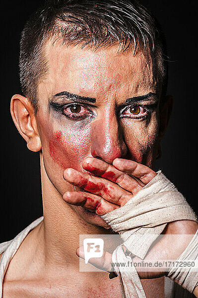 Close-up-Porträt einer weinenden Dragqueen mit Boxverband vor schwarzem Hintergrund