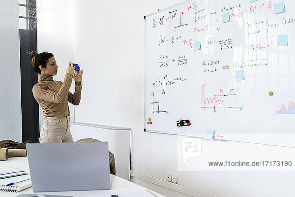 Studentin fotografiert zu Hause stehend die Mathe-Tafel