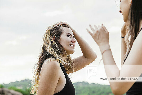Schöne junge Frau mit Hand im Haar  die ihre Freundin anschaut