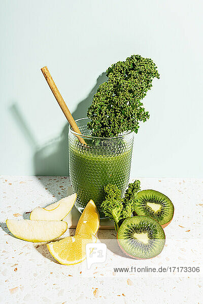 Healthy green juice with apple  lemon  kale  kiwi and celery against wall