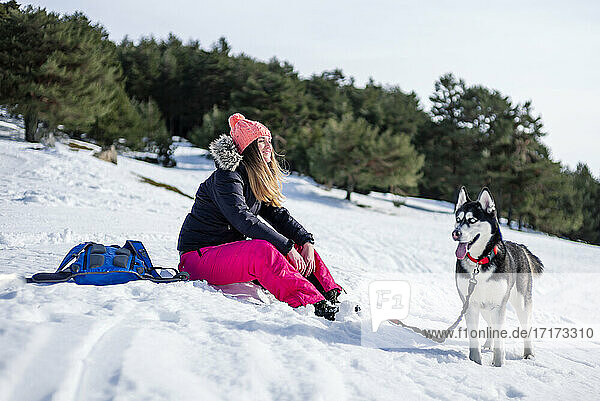 Mid adult woman with Siberian Husky on snow covered field during winter