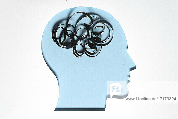 Paper cut out of human head with piece of string representing unordered thoughts
