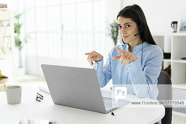 Female customer service representative talking on video call through laptop while sitting at office