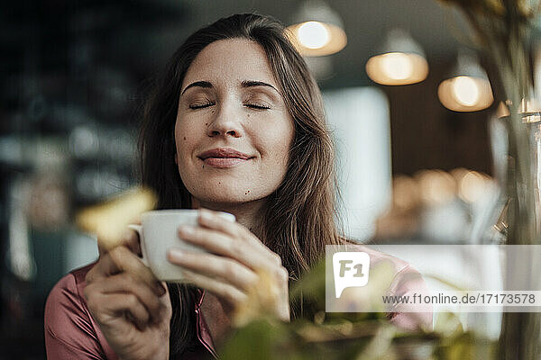 Lächelnde Geschäftsfrau riecht Kaffee im Café
