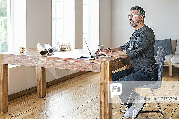 Thoughtful entrepreneur using laptop while sitting at home office