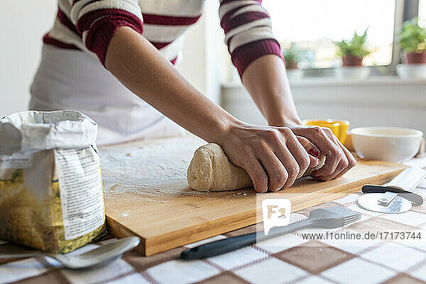 Woman kneading dough for making croissants in kitchen at home