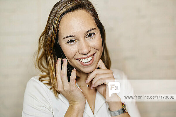 Nahaufnahme einer lächelnden weiblichen Fachkraft  die über ein Smartphone an der Wand spricht