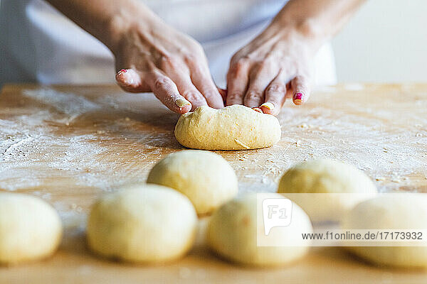 Woman kneading dough balls to make croissants in kitchen