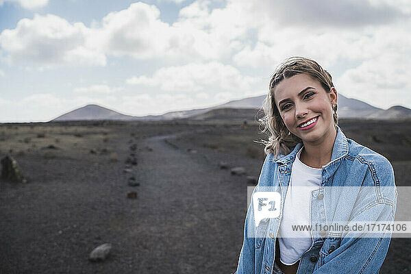 Junge Frau lächelt  während sie am Vulkan El Cuervo steht  Lanzarote  Spanien