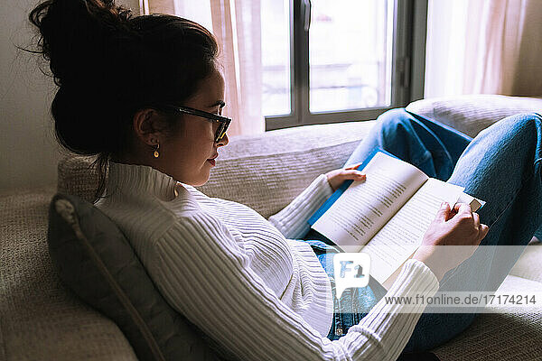 Junge Frau liest zu Hause ein Buch
