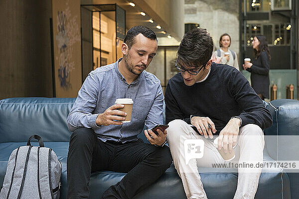 Students on coffee break  looking at phone