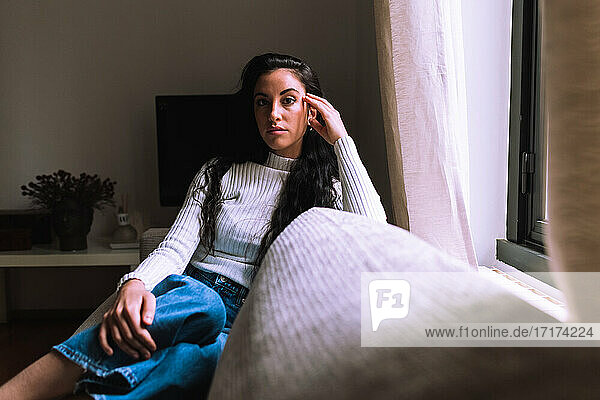Serious young woman sitting on sofa